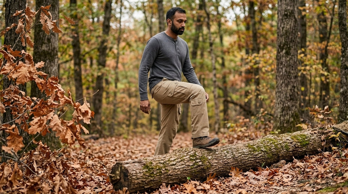 Hiker in khaki ripstop cargo pants taking a high step over a fallen log on an Ozark forest trail in autumn