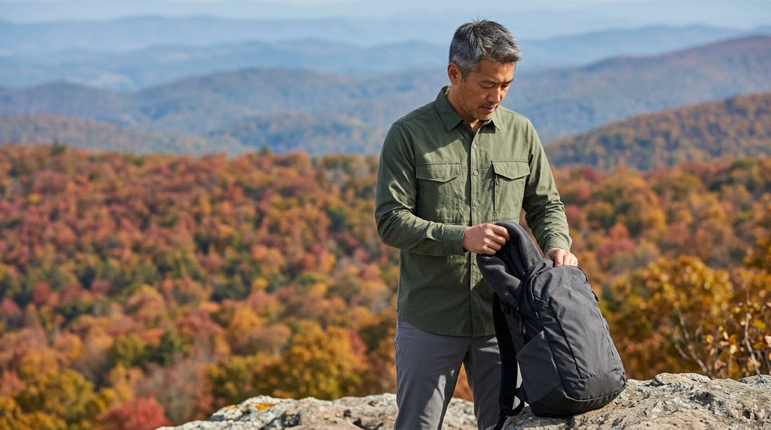Hiker in a long-sleeve quick-dry shirt packing a fleece mid layer on a Blue Ridge overlook in October