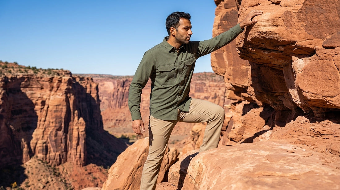 Man in an olive stretch work shirt taking a high step up a red sandstone ledge in southern Utah