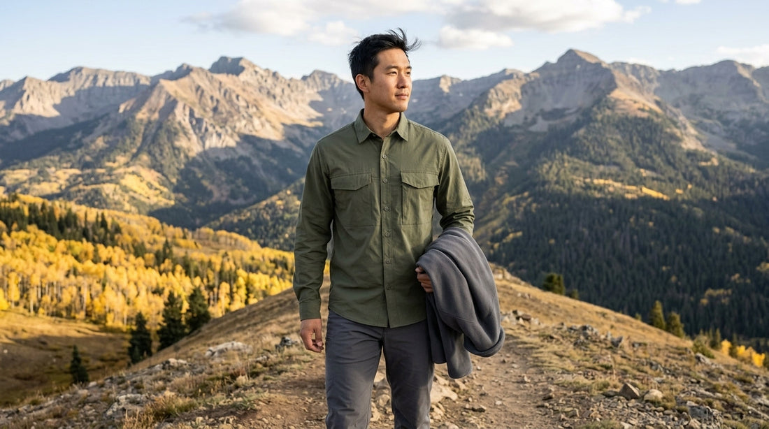 Hiker in an olive long-sleeve stretch shirt carrying a gray fleece on a windy Colorado ridge in fall - softshell vs fleece for fall hiking