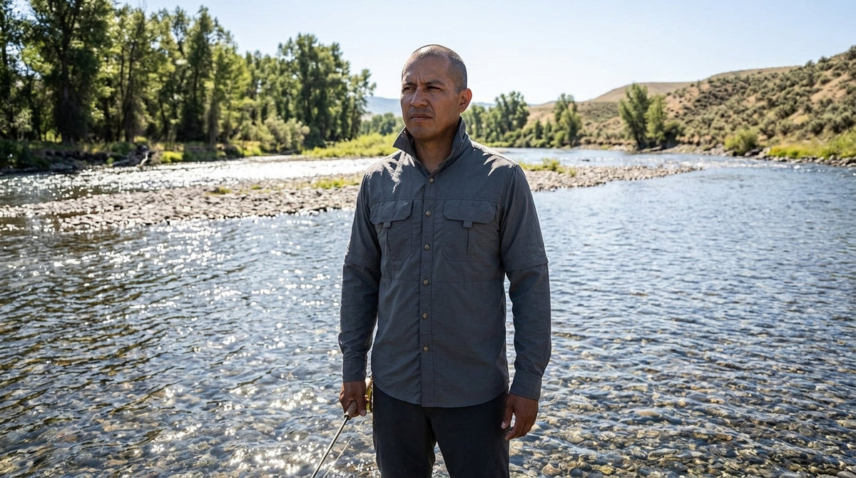 Angler in a grey long-sleeve sun-protective shirt standing in a bright Montana river at midday