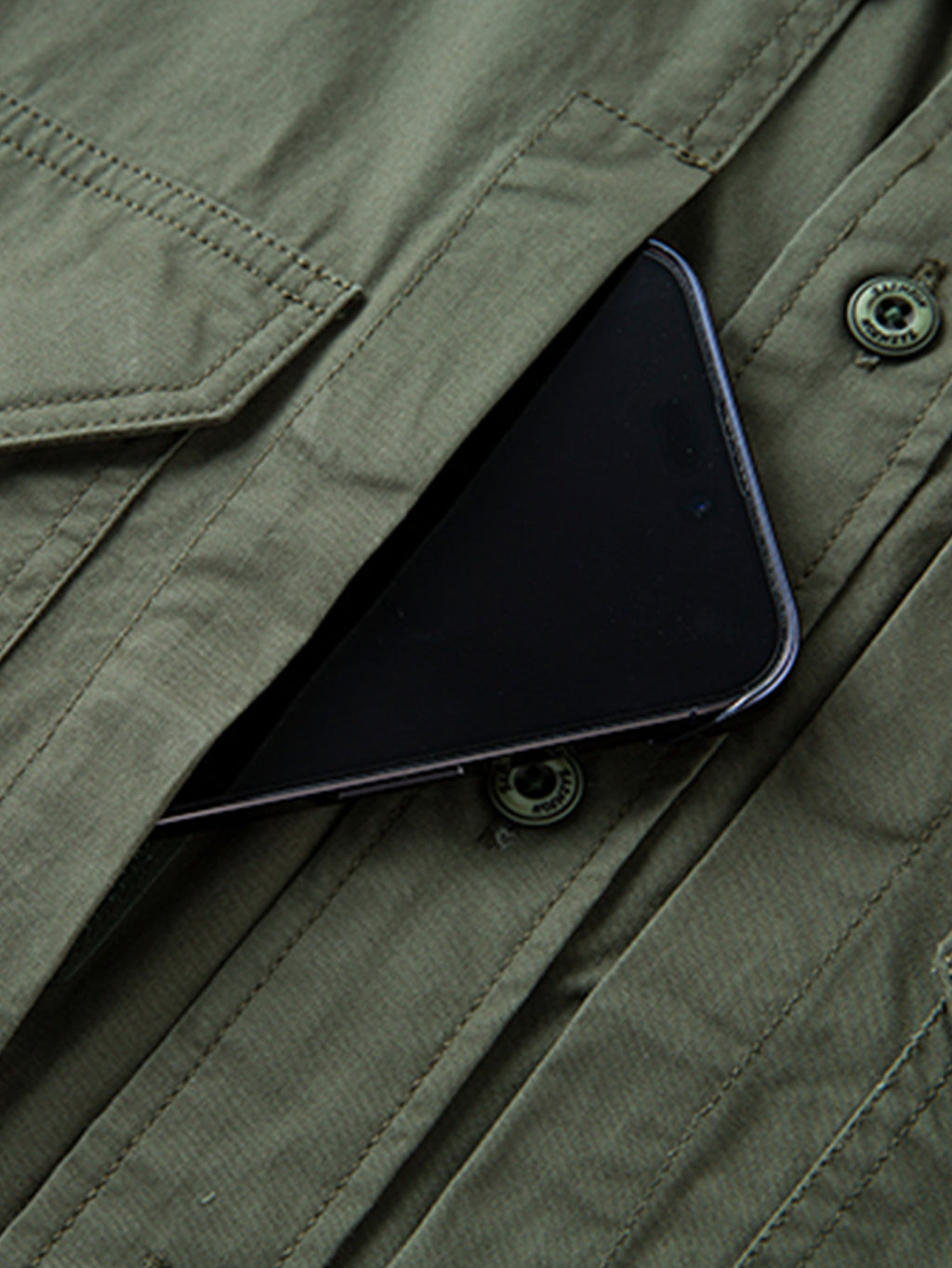 Olive green high-performance outdoor jacket from FREDD MARSHALL with pocket holding phone