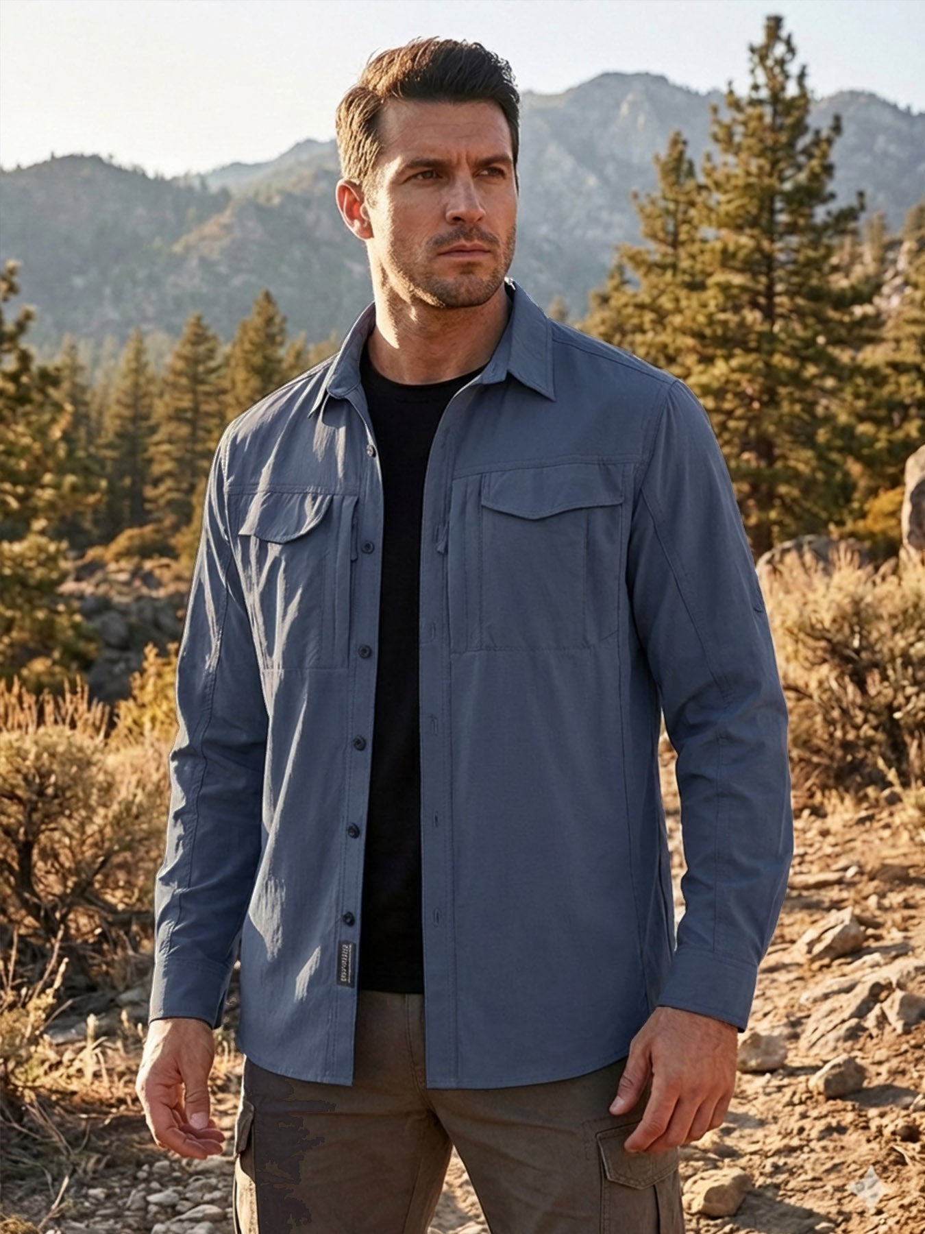 Man in high-performance outdoor shirt by FREDD MARSHALL, standing in a rugged forest setting