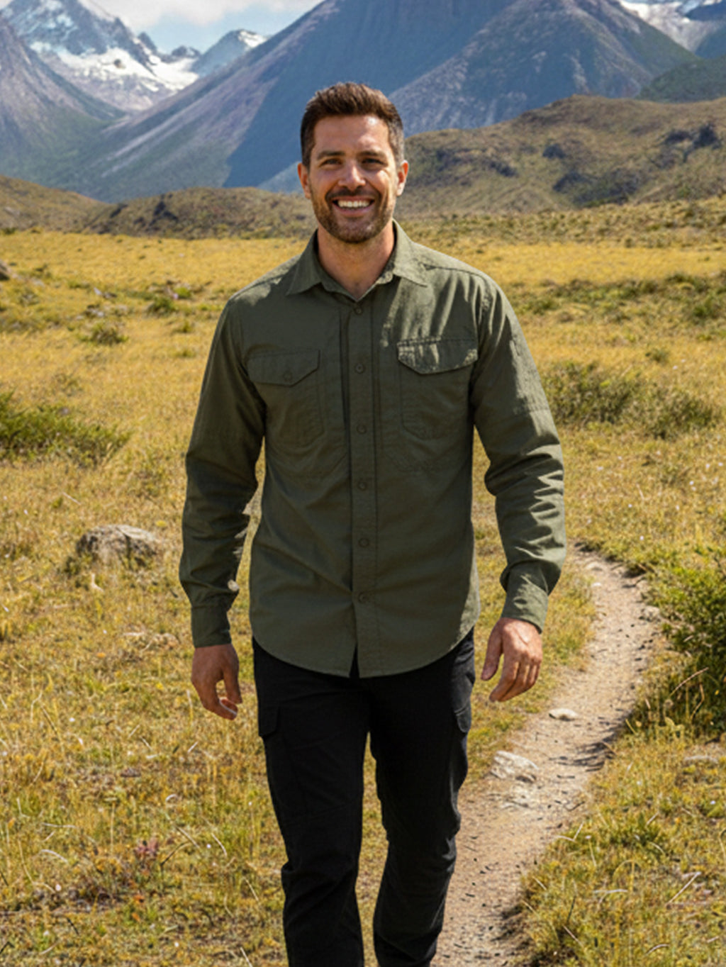 Man in green shirt wearing high-performance outdoor apparel hiking in mountain landscape