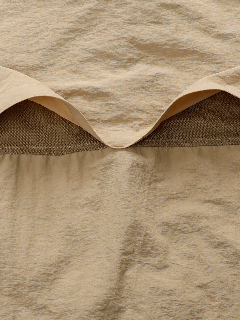 Close-up of high-performance beige outdoor apparel fabric with mesh detail, FREDD MARSHALL